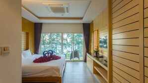 Quarto de hotel com cama, televisão e janela com vista para árvores.