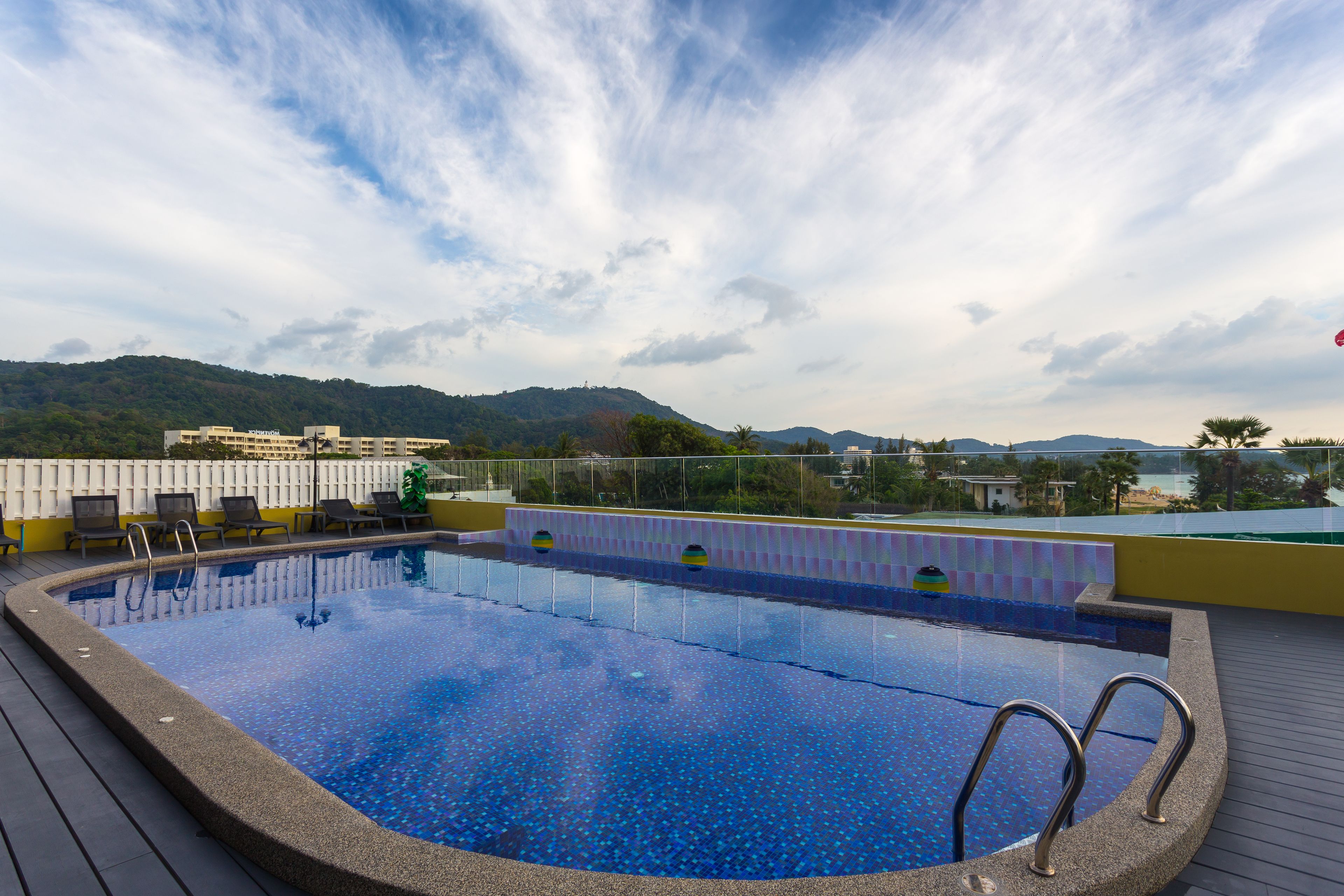 Una piscina en la azotea con vistas despejadas del paisaje circundante, incluyendo colinas y edificios.