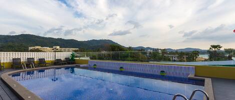 Una piscina en la azotea con vistas despejadas del paisaje circundante, incluyendo colinas y edificios.