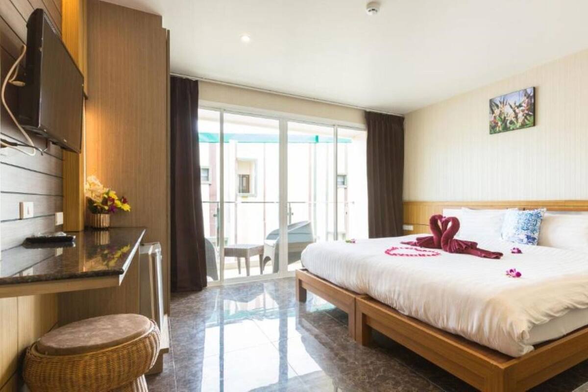 A hotel room with a bed, a desk, a chair, and a view of the outside.
