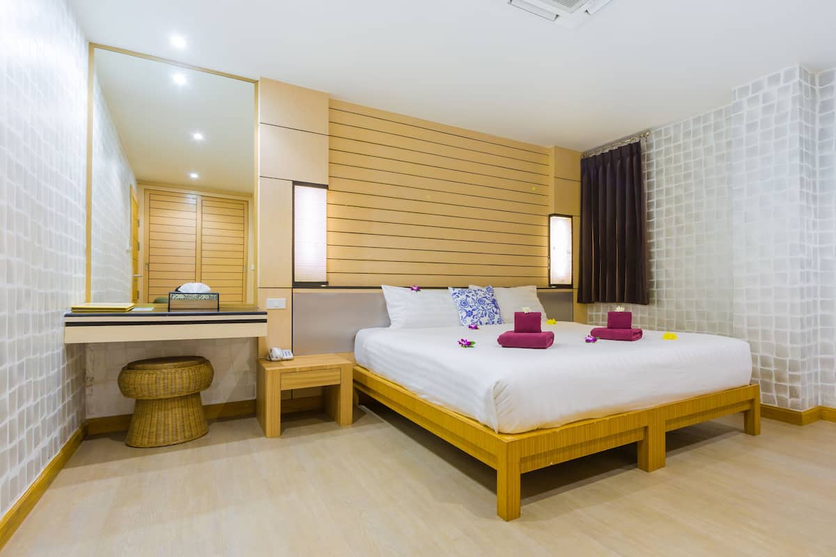 A hotel room with a wooden bed, a bedside table, a mirror, and a large window with curtains.