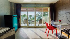 Quarto moderno com uma grande porta de vidro deslizante que dá para uma varanda, uma pequena mesa com duas cadeiras e um frigorífico.