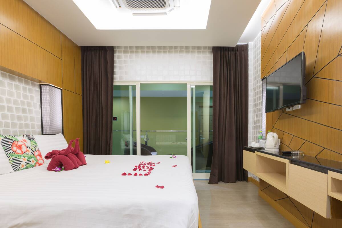 A hotel room with a bed, a TV, a desk, and a sliding door to the balcony.