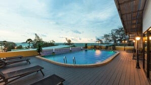 Piscina no terraço com espreguiçadeiras e vista para o oceano.