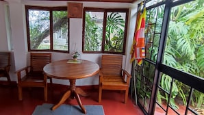 Una habitación con una mesa redonda de madera, cuatro sillas de madera y vistas a abundante vegetación a través de amplios ventanales.