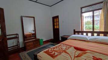 Une chambre à coucher avec un lit, une commode, un miroir, une fenêtre et une porte.