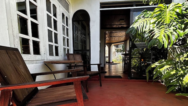 Un patio interior con piso rojo, bancos de madera y una pared de ladrillo con ventanas de arco.