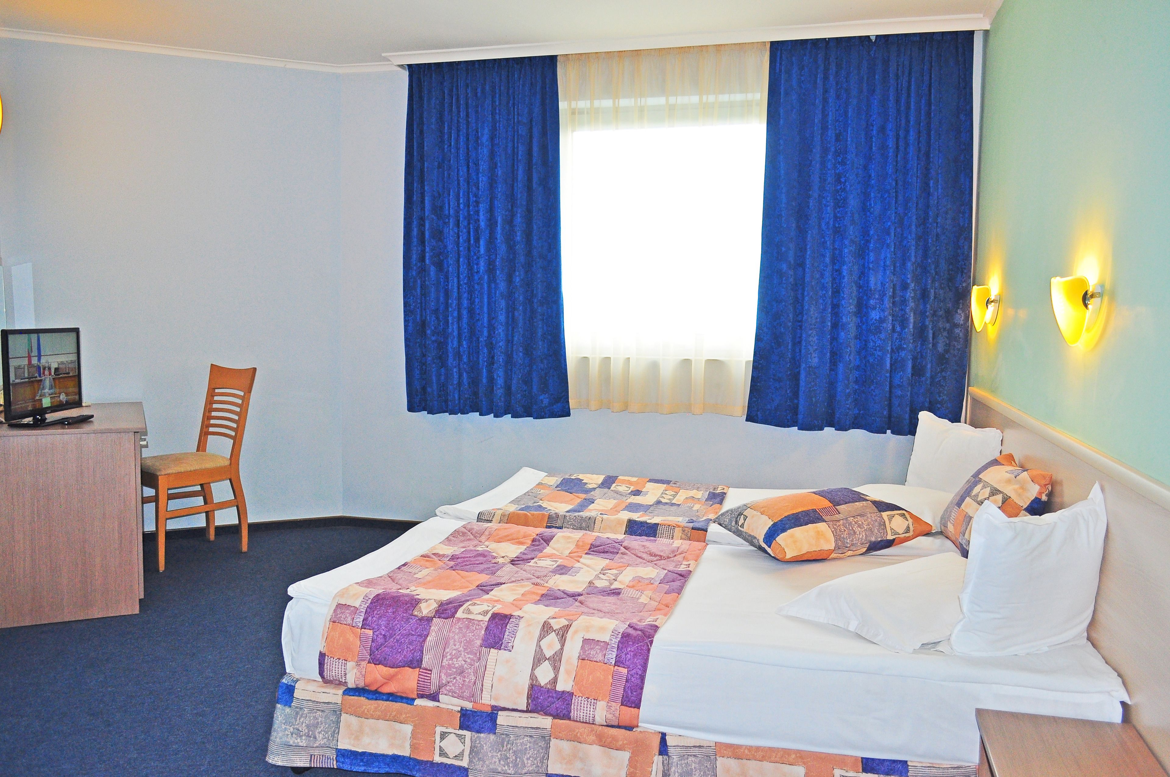 A hotel room with a bed, a desk, and a chair.