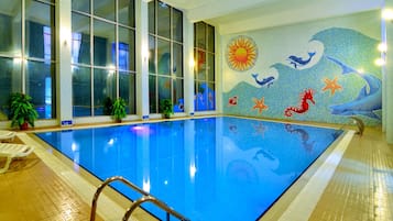 An indoor swimming pool with clear glass walls, a tiled floor, and a mural depicting ocean life.