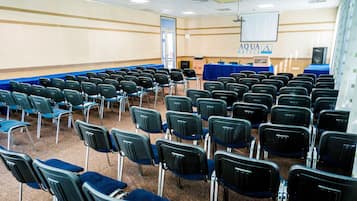 A conference room with rows of chairs, a podium, and a screen.