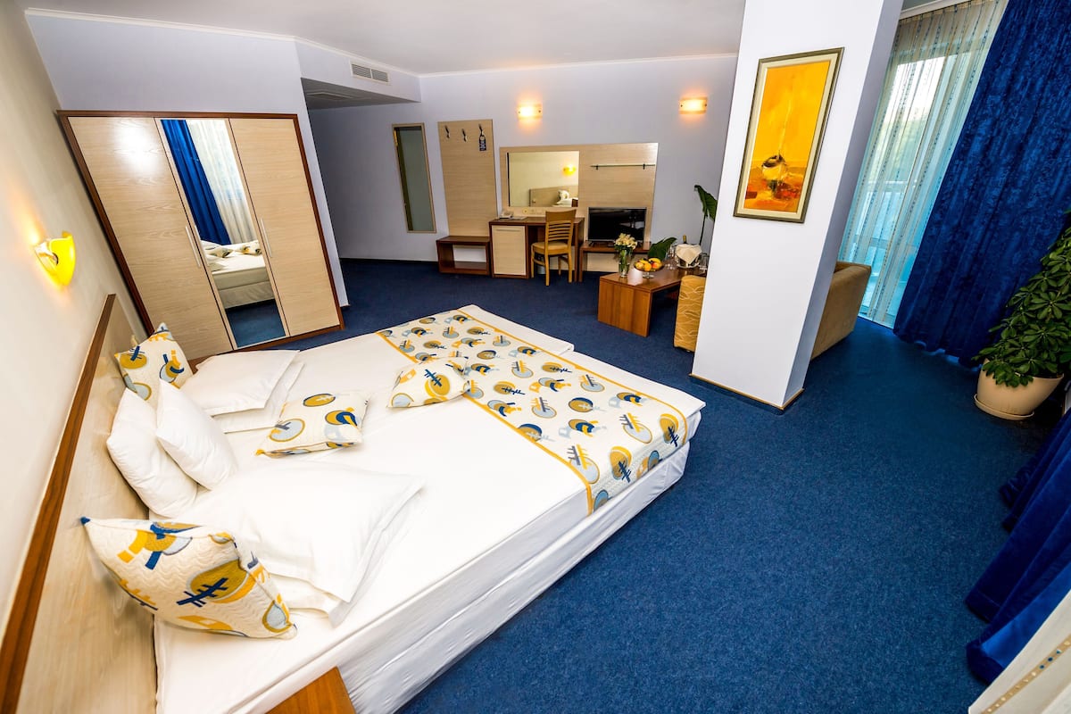 A hotel room with a bed, desk, chair, and a mirror.