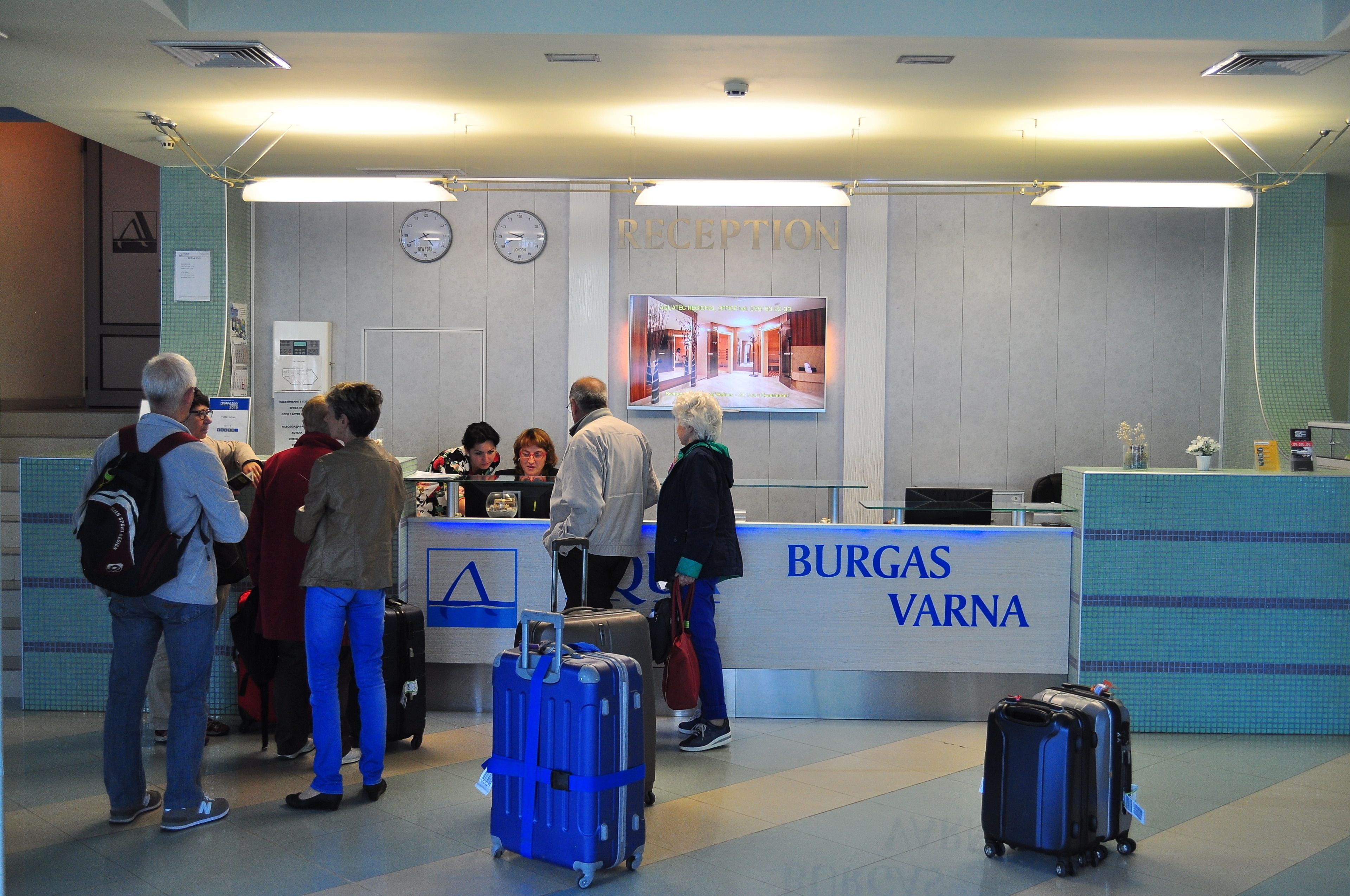 A reception area with a reception desk, a clock, and a digital screen displaying a corridor.