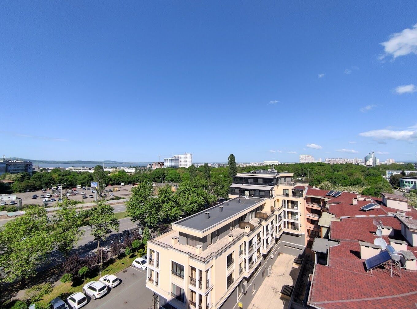 Un edificio de varios pisos con un patio central, rodeado de árboles y coches aparcados.