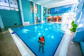 Una piscina interior con superficie de agua cristalina, un trampolín y una silla para salvavidas.