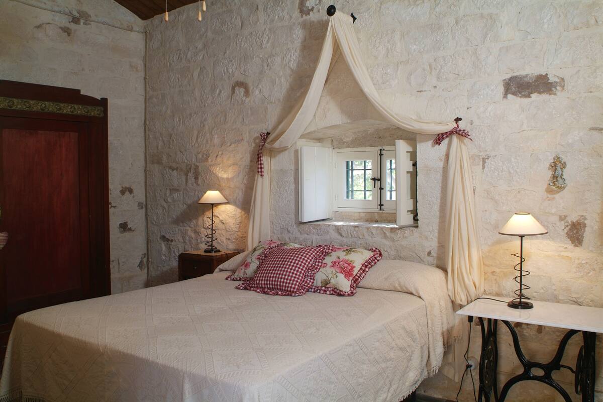 Une chambre à coucher avec un lit, une table de chevet, une lampe de table, un miroir et une porte en bois.