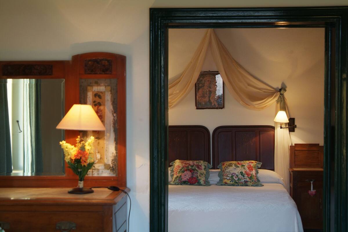 Une chambre à coucher comprenant un lit, une table de chevet, une lampe, une commode et un miroir.