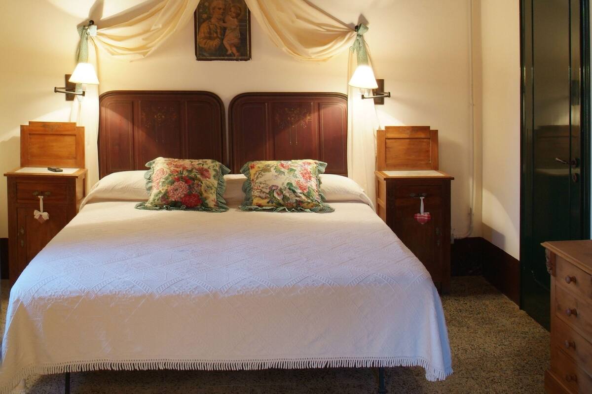 Une chambre à coucher avec un lit à baldaquin, une tête de lit en bois, des lampes de chevet et un ventilateur de plafond.