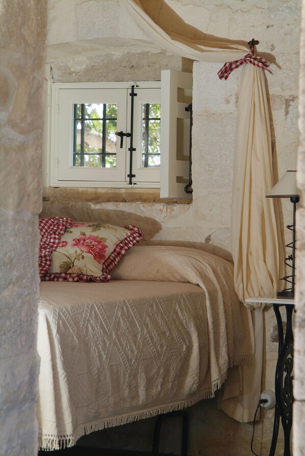 A bedroom with a bed, a window with a curtain, and a lamp. - Agriturismo Masseria Cianciò (Modica)