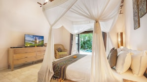 A bedroom with a canopy bed, a wooden dresser, a television, and a view of greenery outside. - Villa Koala (Seminyak)