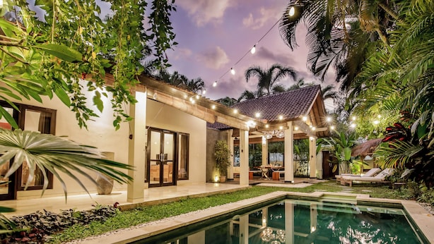 A poolside area with a covered patio, outdoor seating, and lush greenery. - Villa Koala (Seminyak)