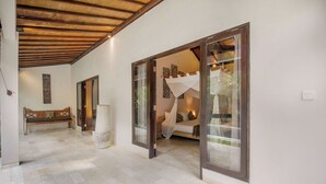 A spacious hallway with a bench, a large pillar, and a bed with a canopy in the background. - Villa Koala (Seminyak)