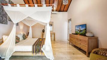 A bedroom with a four-poster bed, a wooden dresser, and a television on a cabinet.