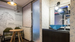 Un bagno d'albergo con un lavandino in vetro blu, una sedia di legno e una mappa appesa al muro.