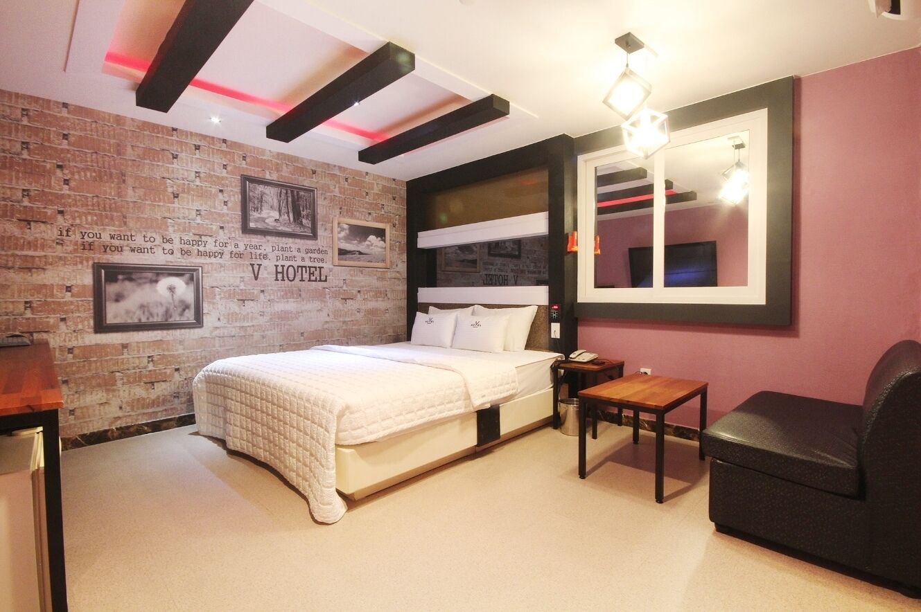 Una camera d'albergo con parete in mattoni, un letto, una scrivania, una sedia e uno specchio grande.