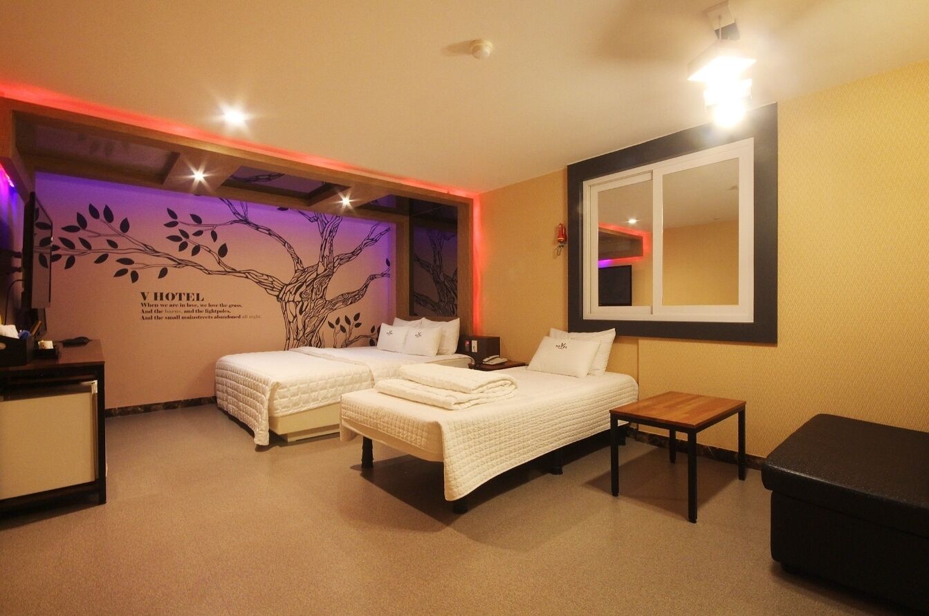 Une chambre d’hôtel avec deux lits, une petite table et un miroir au mur.