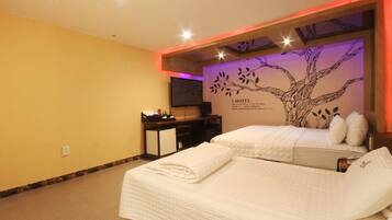 A hotel room with two beds, a desk, a television, and a wall mural.