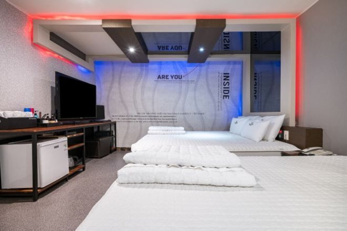 Una habitación de hotel moderna con una cama grande, un televisor de pantalla plana, un escritorio pequeño y un mini bar.