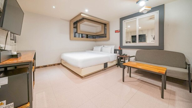 Una camera d'albergo moderna con un letto, un divano, una TV e una scrivania.