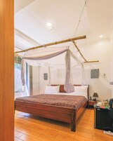 Un dormitorio con una cama con dosel, una mesita de noche, una lámpara y vistas al exterior.