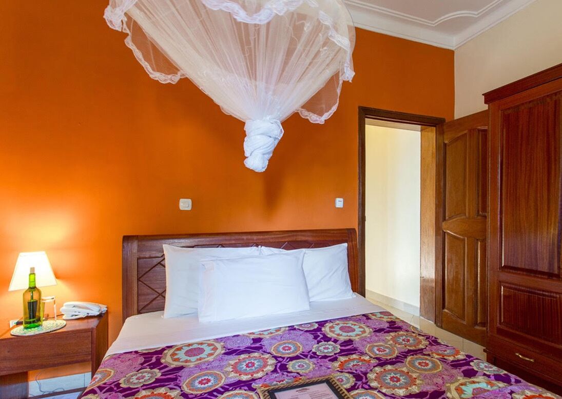 A hotel room with a bed, a nightstand with a lamp, and a wardrobe.