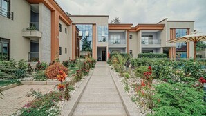 Un edificio moderno con un camino central bordeado por exuberantes jardines y varios balcones.
