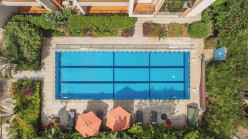 Una piscina al aire libre, sombrillas, sillones reclinables de piscina