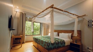 Un dormitorio con cama con dosel, una mesita de noche, un televisor y una ventana con cortinas.