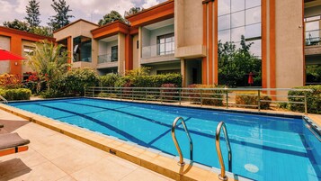 Una piscina al aire libre, sombrillas, sillones reclinables de piscina