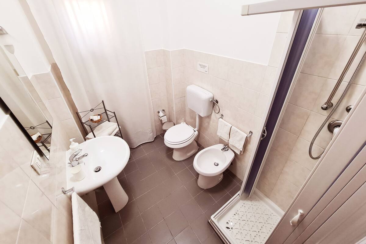 Un baño pequeño con lavamanos, dos inodoros y zona de ducha.