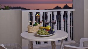 A balcony with a table set for a meal, featuring a basket, fruits, and wine glasses. - Club Paradiso Hotel  (Alanya)