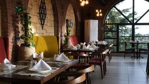 A restaurant with brick walls, large windows, and tables set for dining. - Club Paradiso Hotel  (Alanya)