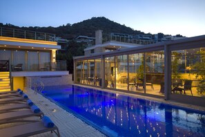 A modern pool area with lounge chairs and a glass-enclosed patio. - Spektr Boutique Hotel Yalıkavak (Bodrum)