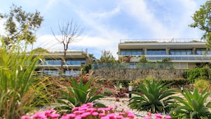 Un edificio moderno con fachada de piedra, rodeado por un jardín ajardinado con diversas plantas y flores.