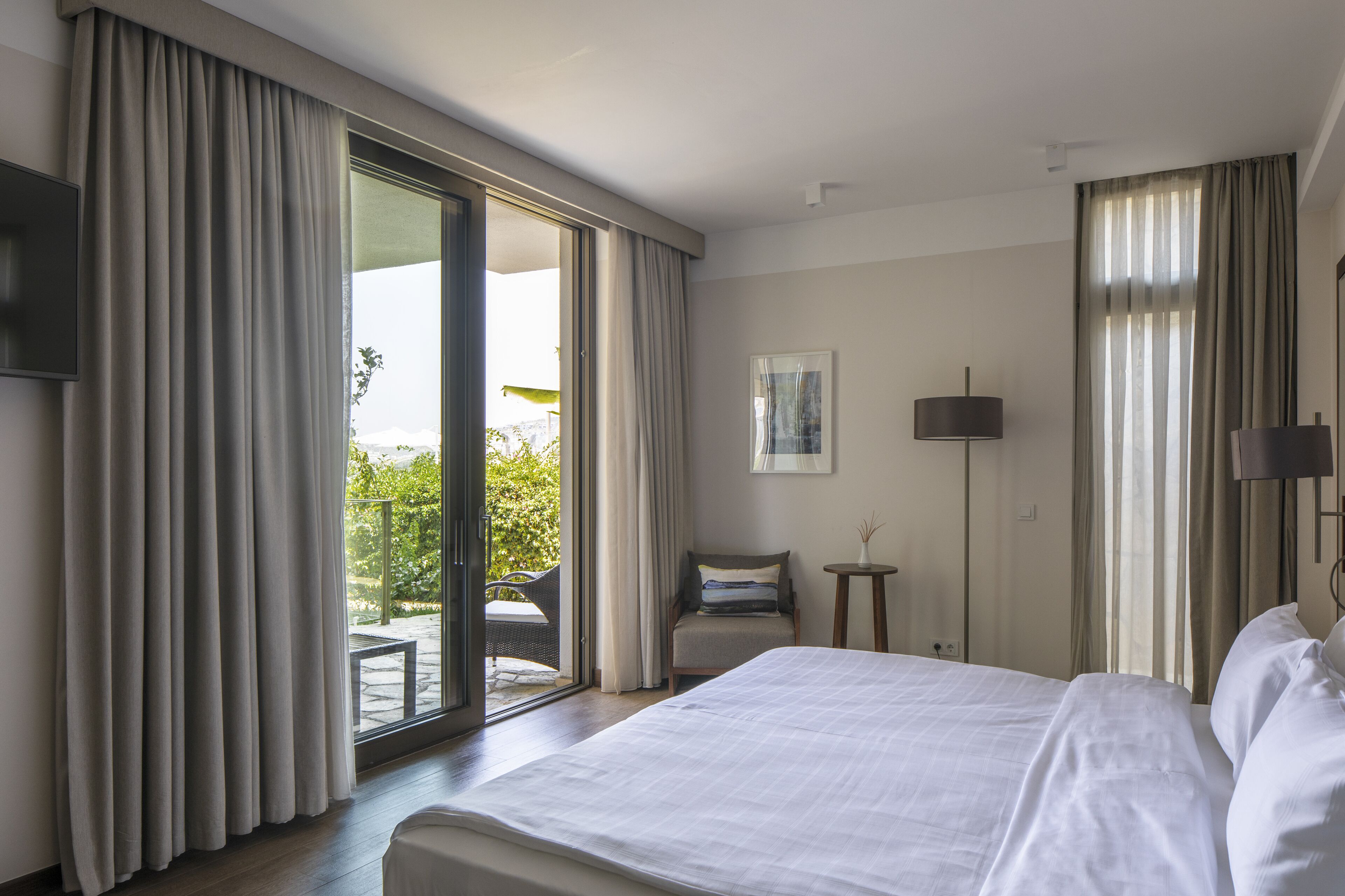 A hotel room with a large bed, a chair, a small table, and a TV.