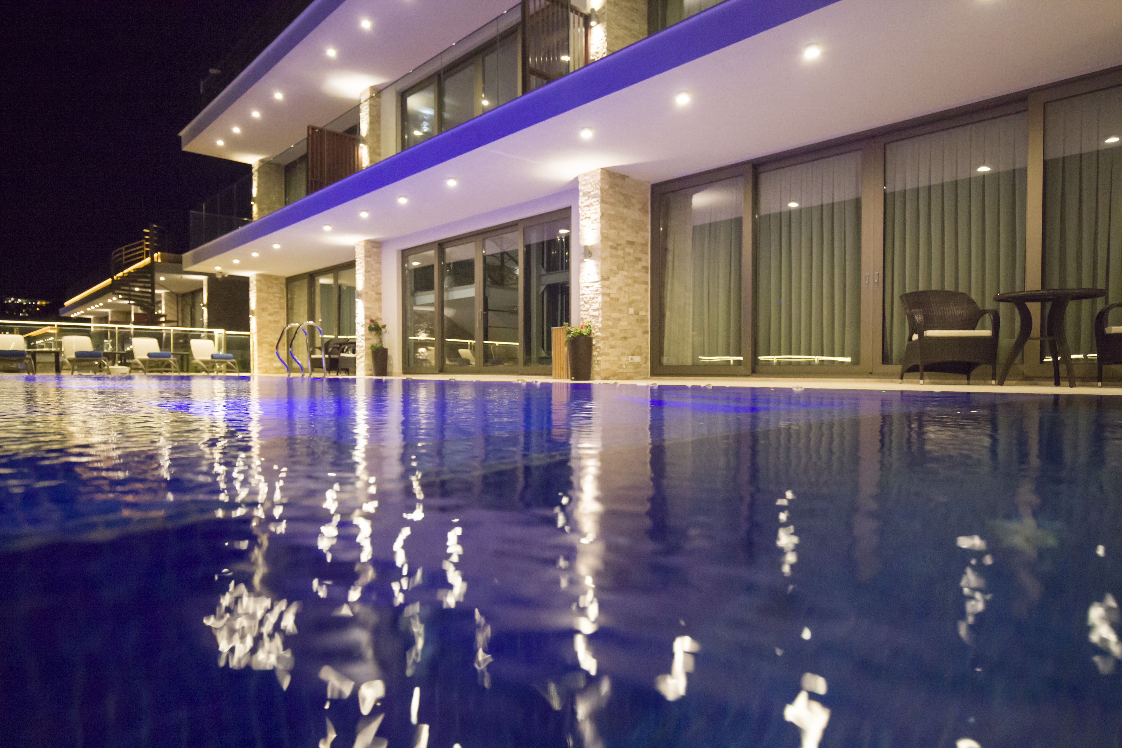 Un hôtel moderne doté d’une piscine, d’un espace extérieur aménagé et de grandes fenêtres.