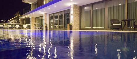 Un hôtel moderne doté d’une piscine, d’un espace extérieur aménagé et de grandes fenêtres.