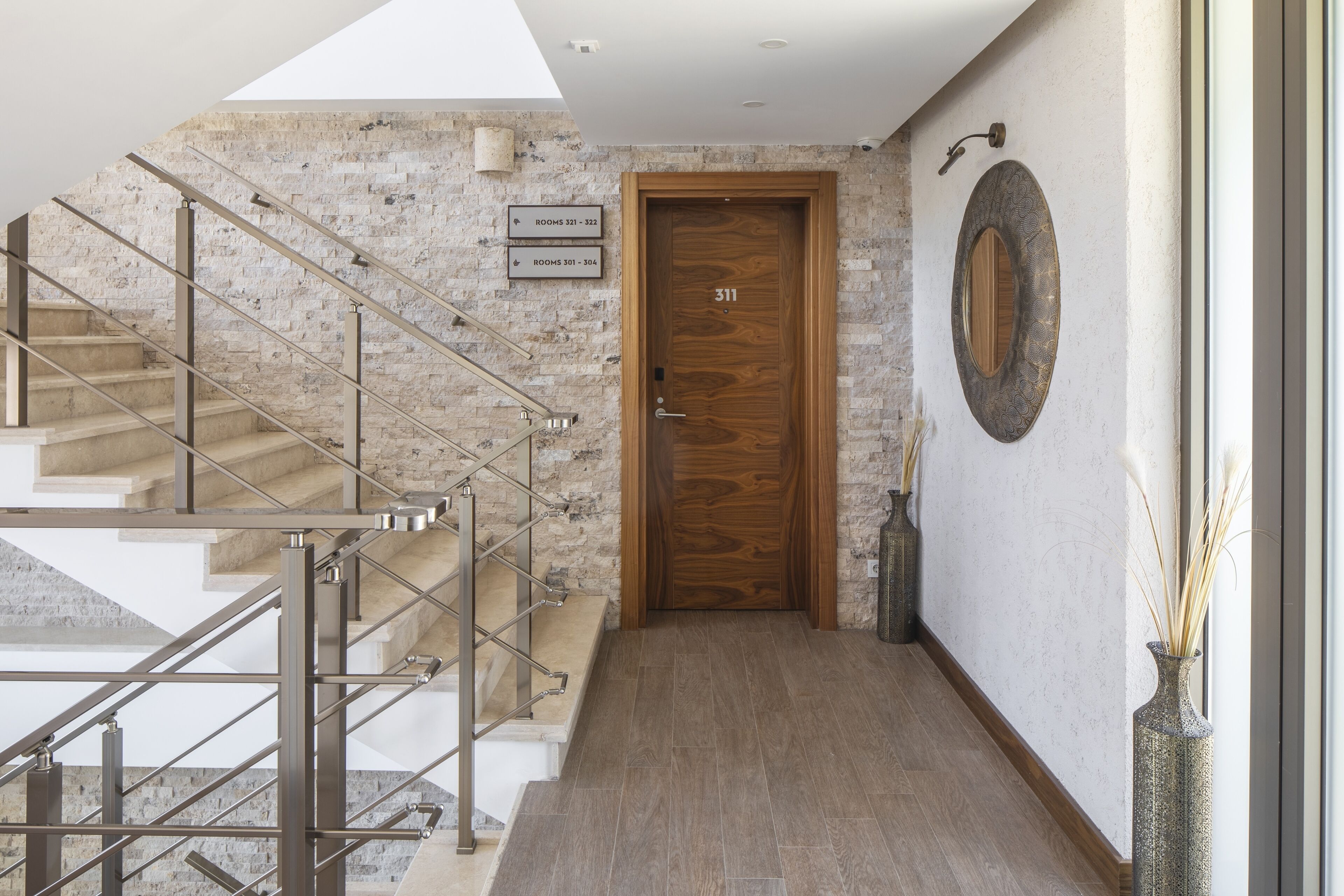 Un interior moderno con una escalera, una puerta de madera con el letrero '311' y un adorno en la pared.