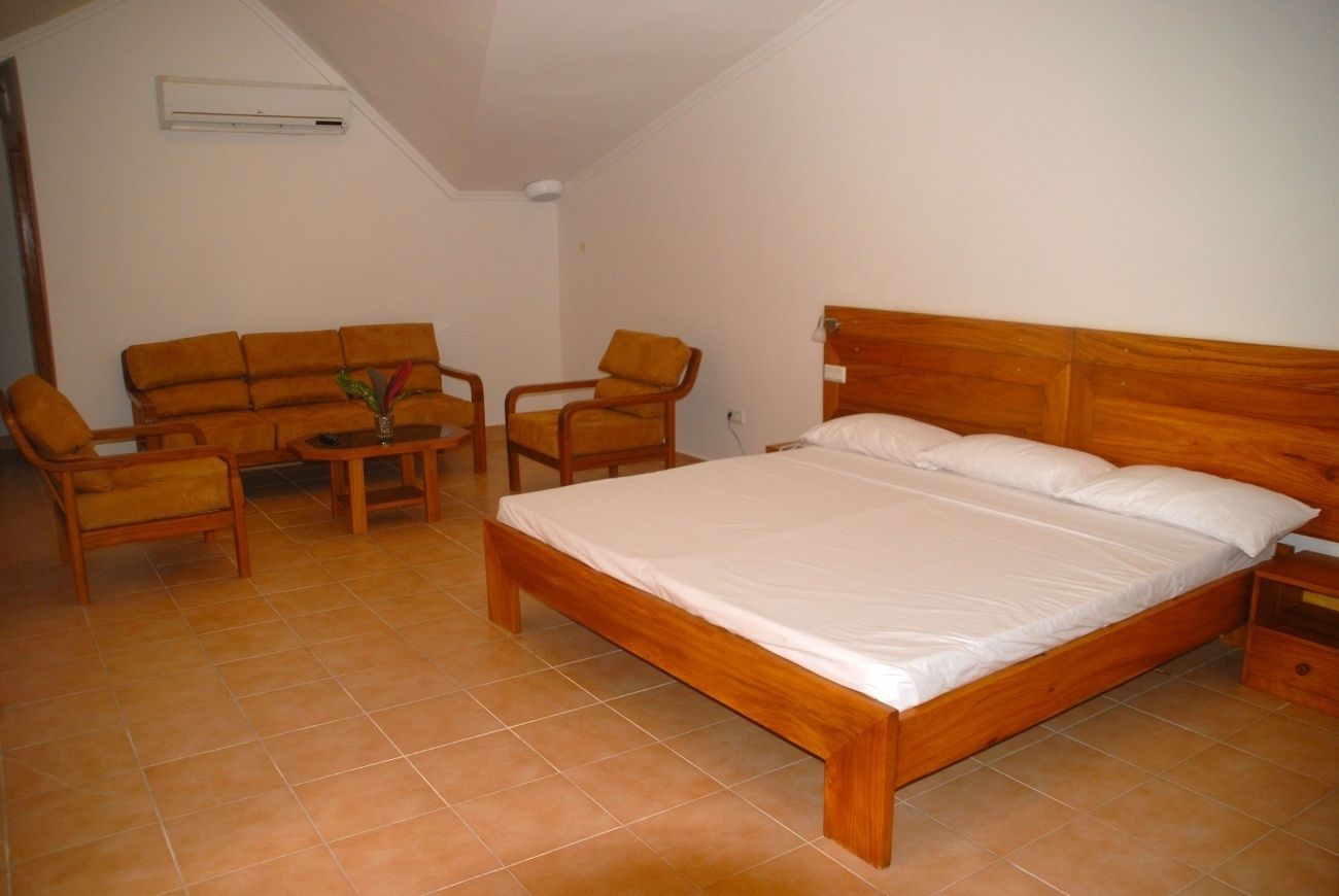Ein Schlafzimmer mit einem hölzernen Bett, einer Schlafcouch, zwei Sesseln und einem kleinen Tisch.