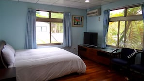 A hotel room with a bed, a desk with a television, and large windows with curtains. - GOOSE NEST Garden B&B (Luye)