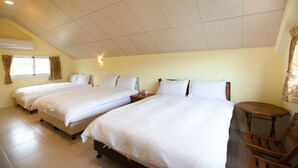 Habitación de hotel con dos camas, una mesita de madera y un ventanal con cortinas.